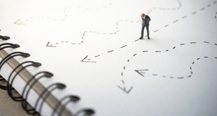 Man looking at directional arrows on notebook paper