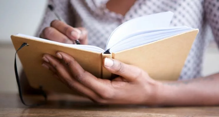 Hand holding open journal on table