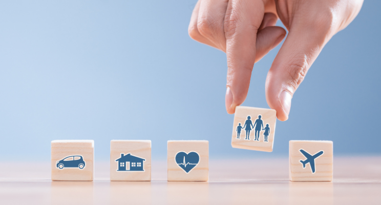 A hand lineing up scrabble pieces with pictures of a house, airplane, family.